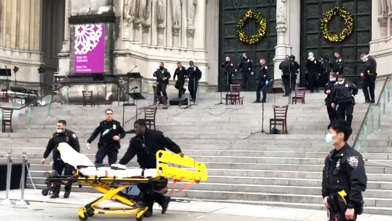 Emergency medical personnel pull a stretcher up to the scene of a shooting at the Cathedral Church of St. John the Divine. Source: Associated Press